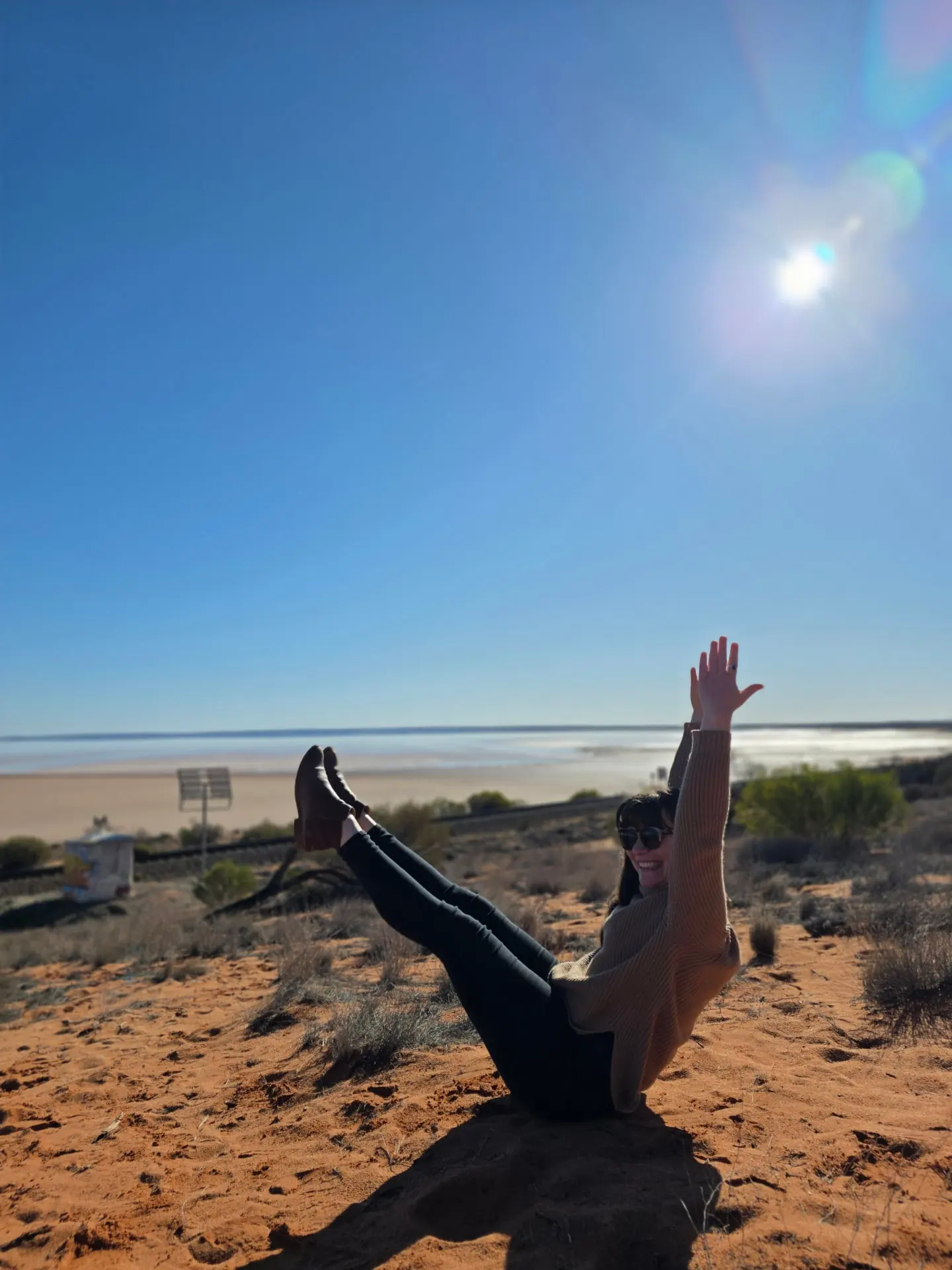 Teaser balance on red sand outdoors, teacher training Pilates Wollongong