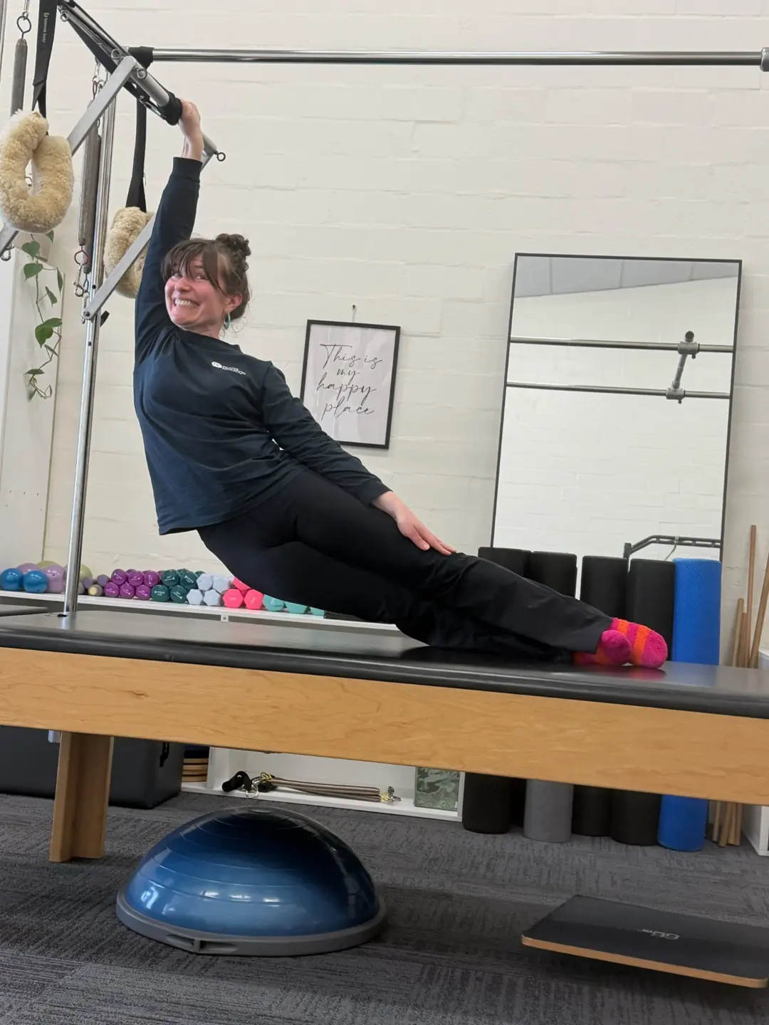 Side reach on the Cadillac holding the trapeze bar, teacher training Pilates Wollongong